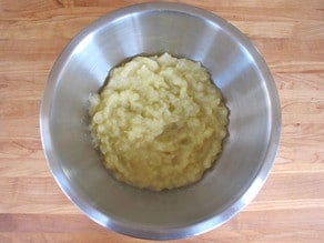 Mashed apples cooling in a mixing bowl.