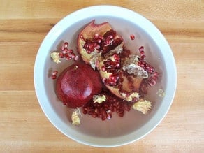 Pomegranate sections submerged in water.