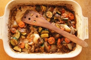 Deglazing baking dish using a wood spoon.