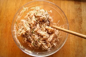 Stirring seasonings into shredded potatoes.