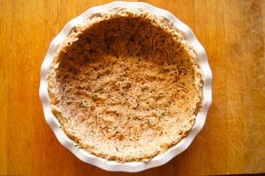 Shredded potatoes pressed into a pie plate.