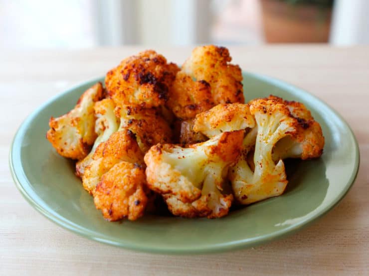 Smoky Roasted Cauliflower served on a color jade plate on top of a wooden table