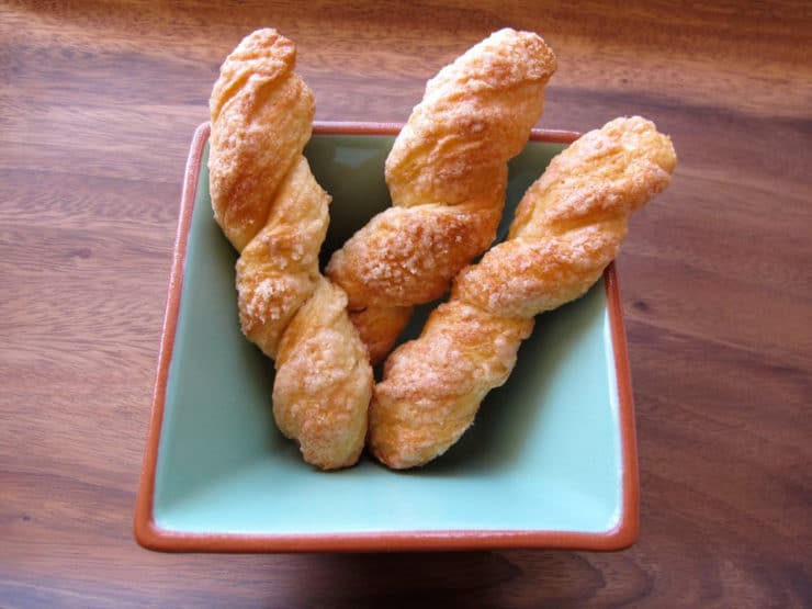 Image of Sour Cream Twists in a rectangular bowl on top of a wood table.