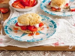 A delectable Strawberry Shortcake topped with fluffy whipped cream on a plate with a spoon on the side