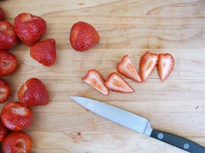 Sliced strawberries on a cutting board.