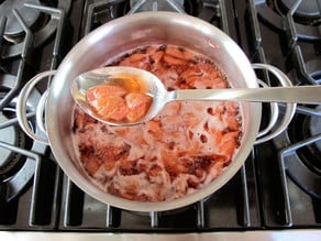 Cooked, sliced strawberries in a saucepan.