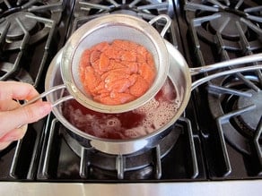 Straining strawberry simple syrup.