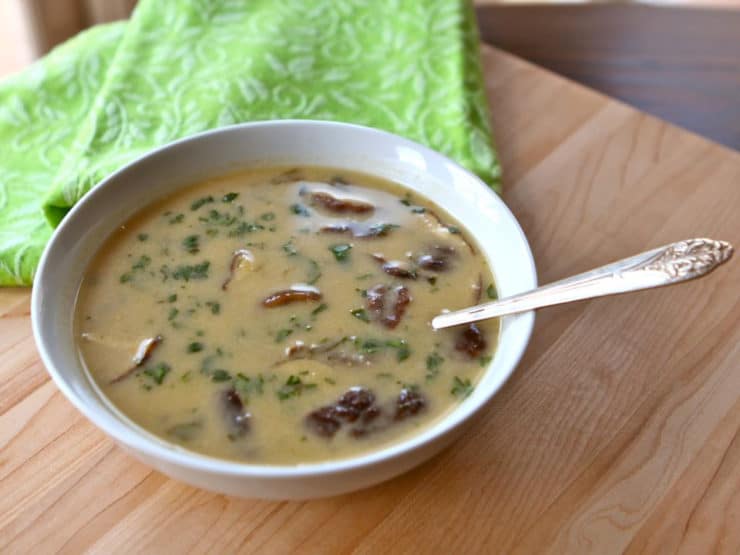 A bowl of coconut soup with red curry paste, coconut milk, and chicken, served with spoon