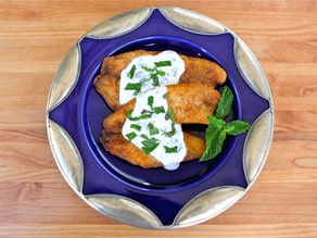 A plate of tilapia topped with a tangy Greek yogurt mint sauce