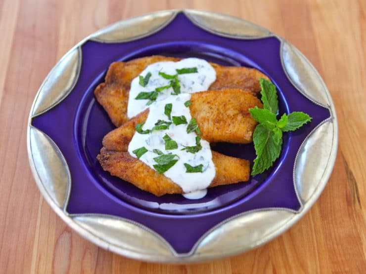 A plate of tilapia topped with a tangy Greek yogurt mint sauce