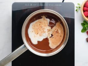 Horizontal overhead shot of a saucepan filled with a mixture of melted chocolate and milk.