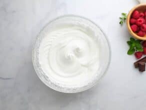 Overhead horizontal shot of a glass mixing bowl filled with whipped egg whites.