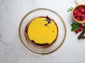 Overhead horizontal shot of a glass mixing bowl filled with a mixture of chocolate almond flour batter and beaten egg yolks.