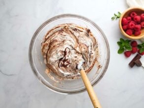 Overhead Horizontal shot of a glass mixing bowl filled with chocolate almond flour cake batter and whipped egg whites being mixed in.