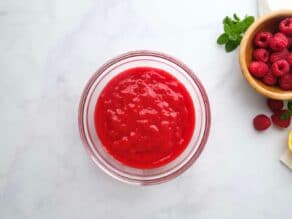 Overhead horizontal shot of a small glass dish filled with strained raspberry puree.