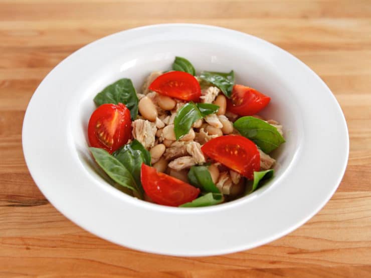 Tuna Salad Caprese made with tomatoes, basil, beans, and tuna served on a white plate