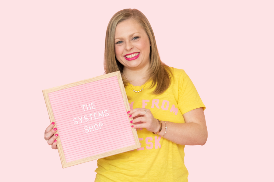 Alexandra of The Productivity Zone holding a pink letterboard with the words The Systems Shop spelled out on it